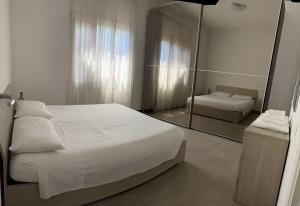 een slaapkamer met een groot wit bed en een spiegel bij Alice’s Home in Bolano