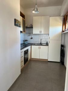 uma cozinha com armários brancos e piso em azulejo em Alice’s Home em Bolano