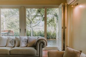 ein Wohnzimmer mit einem Sofa vor einem Fenster in der Unterkunft Carramar Coach House, Romantic Falls Retreat in Wentworth Falls