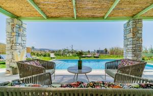 patio con sedie, tavolo e piscina di Plioni Villas & Suites a Mikri Vigla
