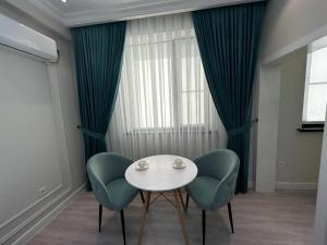 comedor con mesa blanca y 2 sillas azules en Home Apartment Complex, en Shymkent