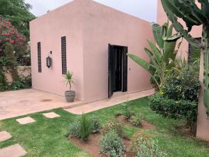 ein rosafarbenes Gebäude mit einer schwarzen Tür und einem Hof in der Unterkunft Pavillon avec piscine privée - AL MAADEN Marrakech in Marrakesch