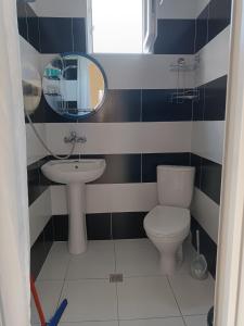 W łazience znajduje się umywalka, toaleta i lustro. w obiekcie Aparthotel Sofia in Gonio w mieście Gonio