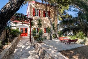 a stone house with red windows and a patio at Villa Gaia - Traditional Stone Villa in Rózia