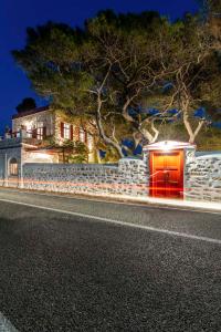 a house with a red door on the side of a road at Villa Gaia - Traditional Stone Villa in Rózia