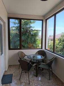 una veranda riparata con tavolo, sedie e finestre di Aparthotel Sofia in Gonio a Gonio
