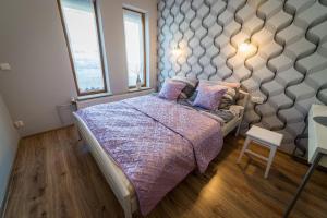 a bedroom with a large bed with purple blankets and pillows at Apartament Mewa Mikołajki in Mikołajki