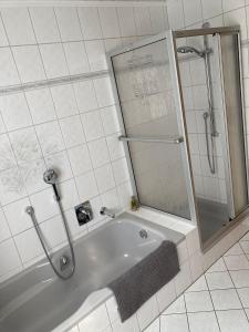 een witte badkamer met een bad en een douche bij Ferienwohnung Gottlieb Extertal Bösingfeld Erholung für 5 Personen in Extertal
