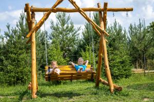 dwójka dzieci bawiących się na huśtawce na polu w obiekcie Puchata Chata - Mazury w mieście Pozezdrze