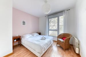 um quarto com uma cama, uma cadeira e uma janela em Appartement Résidence Quartier Vilette Paul Bert BOX GARAGE em Lyon