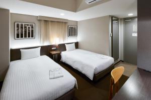 a hotel room with two beds and a tv at Kyoto Itoya Hotel in Kyoto