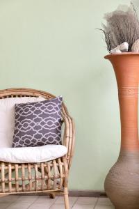 a wicker chair with a blue pillow next to a vase at Sand Dollar 1 Bedroom Oceanfront Apartment A16 in Kralendijk
