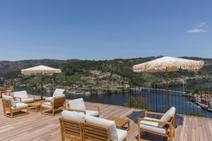 a deck with chairs and umbrellas and the water at QUINTA ALTO DO RIO in Cinfães