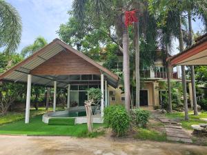 Pool Villa Armthong Home في Ban Nong Toei: منزل فيه مسبح وسط ساحة