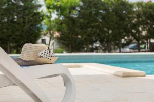 a straw hat sitting on a chair next to a pool at Apartments "Alen" in Nedeščina