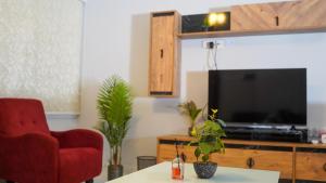 a living room with a red chair and a television at AECO lovely 2 bedroom apartment for family and friends in Muscat