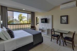 a bedroom with a bed and a table and a window at Flat Pietra in Florianópolis