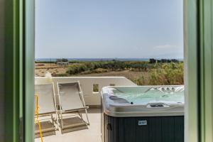 bañera de hidromasaje en el balcón de una casa en Plioni Villas & Suites, en Mikri Vigla