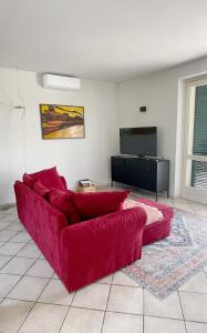 ein rotes Sofa in einem Wohnzimmer mit einem Flachbildfernseher in der Unterkunft Casa da Bertu in Barbaresco + 25 Fotos