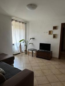 a living room with a television and a tiled floor at Appartamenti Sole e Lago in Gravedona