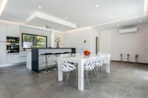 a white kitchen with a white table and white chairs at Villa Vogue by Indigo in Estômbar