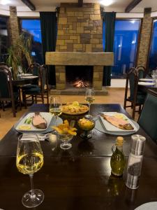 ヴァトラ・ドルネイにあるPensiunea Poiana Izvoarelorのテーブル(2皿の食べ物とワイングラス付)
