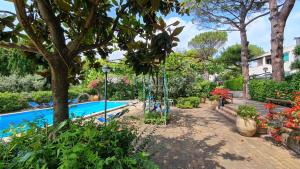 a garden with a swimming pool and trees and flowers at Villa Matisse - Damecuta Park in Anacapri