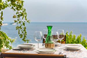 - une table avec des verres à vin et une bouteille verte dans l'établissement Casa Luciana, TerreMarine, Trekking and Nature, à La Spezia