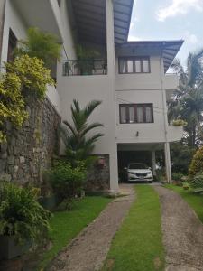 a white house with a car parked in the driveway at Shalom in Peradeniya
