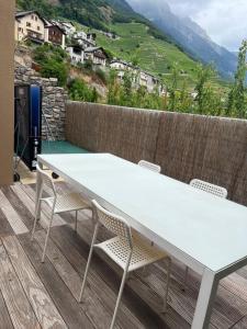 une table et des chaises blanches sur une terrasse avec des montagnes dans l'établissement La Palmeraie, à Fully