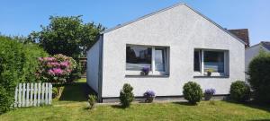 una casa blanca con flores en un patio en Cosy House en Scharbeutz