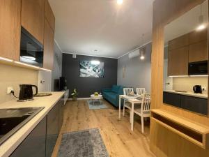 a kitchen and a living room with a blue couch at Caroline Jacuzzi Apartments in Nowy Dwór Mazowiecki