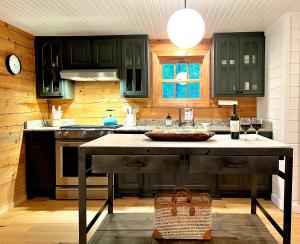 a kitchen with green cabinets and a table with wine glasses at Glass Cabin in Eureka Springs