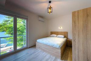 a bedroom with a bed and a large window at Lakeside Luxury Apartments in Jablanica