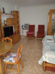 sala de estar con sillas, mesa y TV en Apartamento Bonanza, Playa de Gandía en Los Mártires