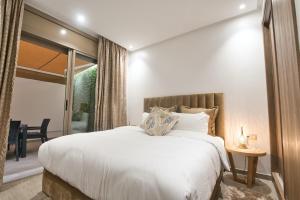 - une chambre avec un lit blanc et une porte coulissante en verre dans l'établissement New Sea Front Apartment 135mq with Unlimited Wi-Fi, à Agadir