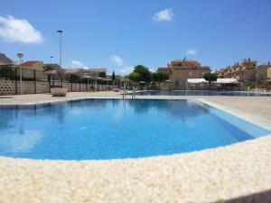 een groot zwembad met blauw water bij Gran Alacant Bea's house in Gran Alacant