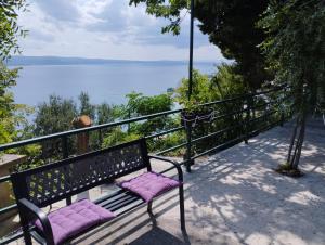 un banc avec des coussins violets assis sur un balcon donnant sur l'eau dans l'établissement House B - with spacious terrace and beautiful view, à Omiš