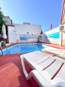 - une piscine avec 2 chaises longues blanches à côté dans l'établissement ApartHotel Maison Suisse, à Asuncion