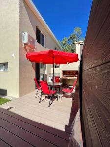 eine Terrasse mit roten Stühlen, einem Tisch und einem Sonnenschirm in der Unterkunft Casa para 4 personas en vista24uy, Bella Vista, Maldonado in Balneario Solís