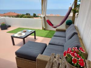 a couch sitting on a balcony with a hammock at Casa Moinhos do Mar in Ericeira