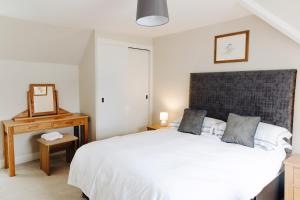 a bedroom with a large white bed and a mirror at Inn at Port nan Gael in Pennyghael