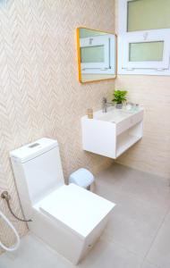 a bathroom with a toilet and a sink and a mirror at AECO lovely 2 bedroom apartment for family and friends in Muscat