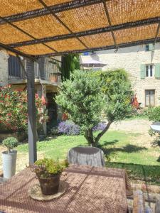 a table and chair under a pergola with a tree at So Home in Saint-Pantaléon-les-Vignes