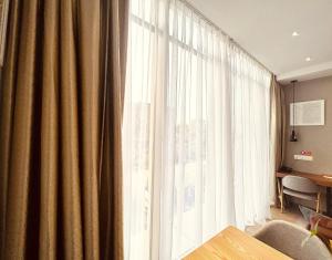 a living room with a large window with curtains at oxy suites 1-01 at Shop House Meisterstadt Pollux Habibie in Batam Center