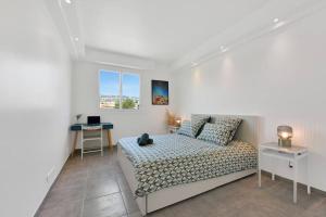 ein weißes Schlafzimmer mit einem Bett und einem Schreibtisch in der Unterkunft CROISETTE BEACH - Modern 2 Bdrs Best Location! in Cannes