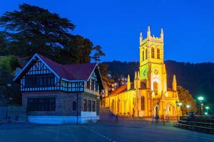 uma igreja com uma torre de relógio à noite em Shimla Royale - Near Mall Road Free Pickup From Railway Station Shimla em Shimla