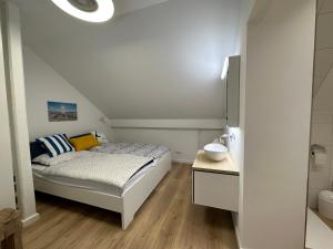 a small bedroom with a bed and a bathroom at MEERzeit unter Reet in Braderup