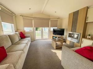 ein Wohnzimmer mit einem Sofa und einem TV in der Unterkunft Caravan With Decking And Free Wifi At Seawick Holiday Park Ref 27214sw in Clacton-on-Sea