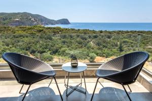 two chairs and a table on a balcony with a view of the ocean at Aigli Skala Maries Deluxe in Skala Marion